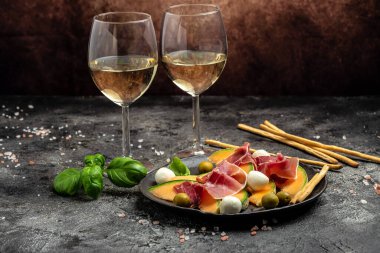 Akdeniz salatası jambon, mozzarella ve yeşil fesleğen yaprakları ve kavun kavunu beyaz masada, geleneksel İspanyol ve İtalyan aperatifi toptan Grissini ile servis edilir..