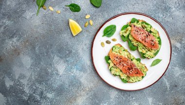 Lezzetli bir kahvaltı ya da avokado ezmeli ve somonlu tam tahıllı ekmek. Keto Paleo diyeti. afiş, menü, metin için tarif yeri, üst görünüm.