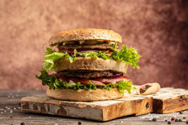Ev yapımı hamburger, ızgara et, sebze, ahşap arka planda sos. Fast food ve abur cubur kavramı,