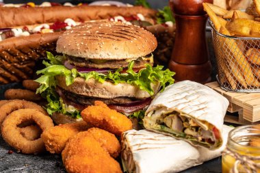 Çeşitli fast food çeşitleri, ev yapımı lezzetli hamburger ve kızarmış tavuklu sosisli patates kızartması. Radyasyon Amerikan yemekleri. fast food.