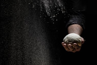 Beyaz takım elbiseli pasta şefi beyaz toz kaplı masaya top hamuru fırlatırken beyaz un havaya uçuyor. Doğa, İtalya, gıda, diyet ve biyoloji kavramı.