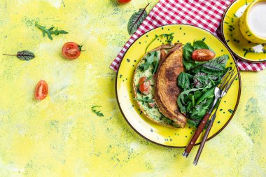 Taze sebzeli ve peynirli frittata. Sarı tabakta İtalyan omleti ve ıspanak salatası. Ketogenik, keto yemeği. afiş, menü tarifi üst görünümü.