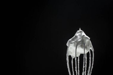 Siyah tepeler için çırpılmış yumurta çırpmak için çırpılmış metal çırpma kreması. Krem şanti, kurabiye tarifi.