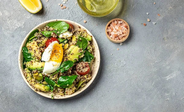 Keto diet plate quinoa, avocado, egg, tomatoes, spinach and sunflower seeds on light background. Healthy food, ketogenic diet, diet lunch concept, place for text, top view.