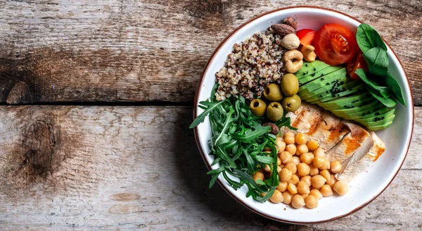 Buddha bowl with kale salad, quinoa, chicken fillet, chickpeas, avocado, spinach, tomatoes cherries, nuts arugula, Clean eating dieting food concept. Long banner format. top view.
