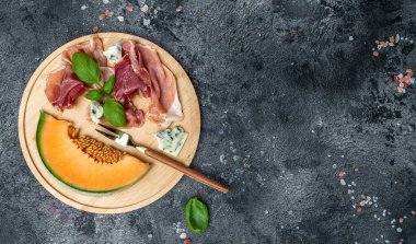 Aperatif, jambonlu kavun ve Basil. Antipasti, İtalyan yemeği. Koyu masanın üst manzarası. Uzun afiş biçimi. en üstteki görünüm.