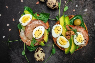 Tam ekmekli iki tost, yumurta, ıspanak, avokado, koyu arka planda karides, ketogenik kahvaltı. Süper yiyecek konsepti. Sağlıklı, temiz yemek. Üst görünüm.