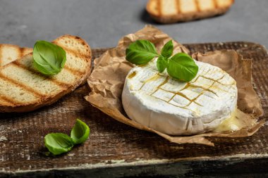 Fırında kamembert peyniri ve fesleğen yaprağı. Köy masasında ev yapımı ızgara peynir. afiş, menü, metin için tarif yeri, üst görünüm.