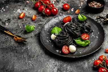 Siyah makarna salata domatesleri, mozzarella ve yeşil fesleğen yaprakları. Mürekkepbalıklı makarna. afiş, menü, metin için tarif yeri, üst görünüm,