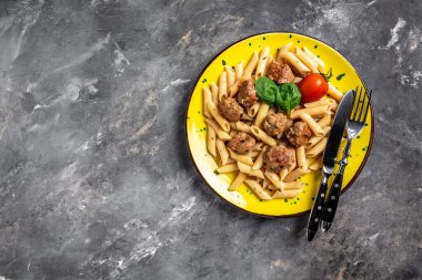 Köfteli makarna ve sarı tabakta domates sosu ve gri arka plan. Mutfak, yemek pişirme, fırın konsepti, afiş, metin için menü tarifi yeri, üst görünüm,