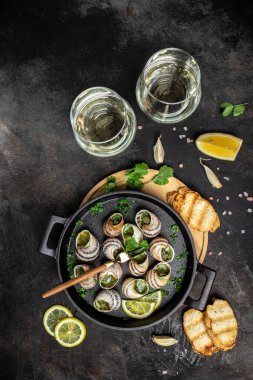 Soslu salyangoz, salyangoz salyangoz ve şarap kadehi. Tereyağı ve baharatlı fırında salyangoz. Gurme yemekleri. dikey görüntü. Üst Manzara. metin için yer.