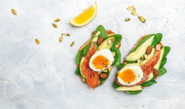 Avokado ezmeli ve somonlu tam tahıllı ekmek. Keto Paleo diyeti. Lezzetli kahvaltı ya da atıştırmalık. Uzun afiş biçimi. en üstteki görünüm.