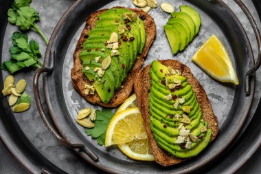 Avokado, çavdar ekmeği, dilimlenmiş avokado. Vejetaryen vejetaryen menüsü, tarif. Lezzetli kahvaltı ya da atıştırmalık, temiz yemek, diyet, vejetaryen yemek konsepti. en üstteki görünüm.