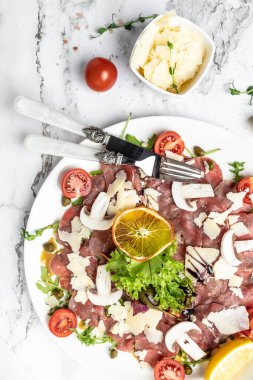 Parmesanlı sığır eti, kapari ve hafif arkaplanlı roka. Soğuk meze. dikey görüntü. Üst Manzara. metin için yer.