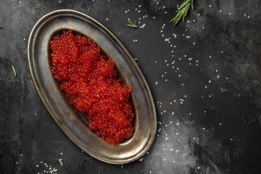 Koyu arkaplanda kaliteli tabakta lezzetli kırmızı havyar. Pankart, menü, tarif. seçici odak, metin için yer.