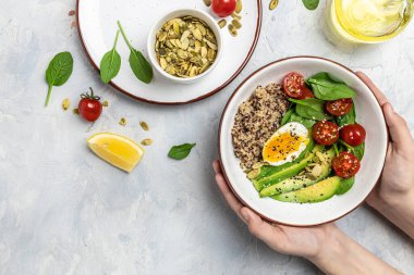 Avokado, yumurta, domates, ıspanak ve ayçiçeği tohumlu kadın eli. Ev yapımı yemek. Sağlıklı, temiz yemek. Vegan ya da glütensiz diyet, metin yeri, üst görünüm.