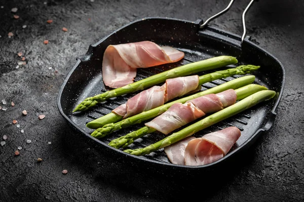 Kuşkonmaz ve pastırma. Jambona sarılı kuşkonmaz, arka planda ızgarada pişmeye hazır, yemek tarifi arka planında. Kapat.,