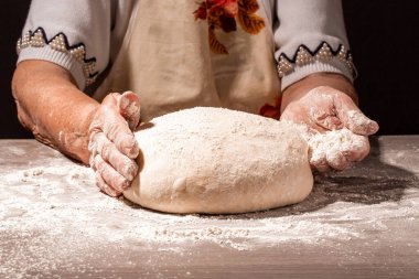 Ekmek, büyükannenin kırışık ellerinde, yakın planda. Büyükanne ekmek hamuru. Büyükanne elinde buğday kulaklı bir parça ekmek tutuyor. Ekmeği olan yaşlı kadın..