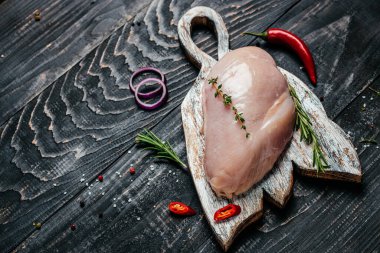 Koyu bir arka planda ahşap bir tahta üzerinde hindi filetosu, yemek malzemeleri. Üst Manzara. metin için yer.