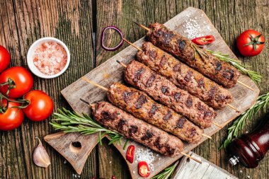 Sığır eti kıyma üzerinden bir çubuk üzerinde şiş kebap. Lula kebap, geleneksel Kafkas çanak. Ketçap ile bir kesme tahtası üzerinde betonun siyah arka plan üzerine alan yukarıdaki baharat ve domates kopyalama