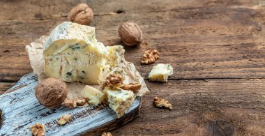 Danimarka mavi peyniri. Ahşap arka planda ve çuval bezinde leziz bir mavi peynir. Dorblu peynir parçaları. Uzun pankart biçimi.