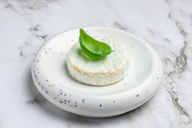 Fesleğen yapraklı Camembert peyniri. Yuvarlak brie peyniri ya da beyaz tabakta camambert peyniri. Yer mantarı peyniri. Yemek tarifi geçmişi. Kapat..
