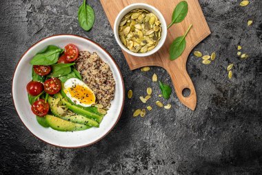 Keto diyet tabağı kinoa, avokado, yumurta, domates, ıspanak ve ay çekirdeği. Sağlıklı yiyecekler, ketojenik diyet, diyet öğle yemeği konsepti, metin yeri, üst görünüm.