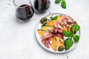 Jambonlu kavun, jambonlu kavun ve bir bardak şaraplı yeşil fesleğen yaprağı. Hafif arka planda nefis süper yemek salatası, geleneksel İtalyan atıştırmalık antipasti. metin için yer, üst görünüm.