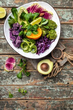 Tatlı patatesli vejetaryen salatası, brokoli, avokado, mor lahana, salatalık, karpuz turpu ve ahşap zemin üzerinde badem. Temiz yemek, diyet yemek konsepti. en üstteki görünüm,