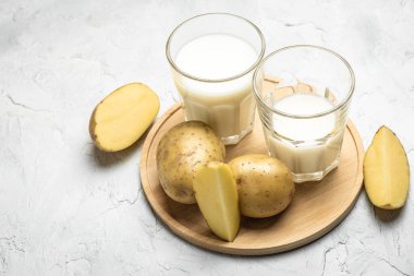Bardakta vejetaryen patates sütü ve çiğ patates. Alternatif bitkisel süt. Süper yiyecek konsepti. Sağlıklı, temiz yemek. Vejetaryen ya da glütensiz diyet. en üstteki görünüm.