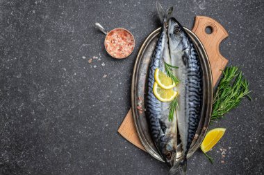 Siyah arka planda tuzlu, limonlu ve baharatlı uskumru. Taze deniz ürünleri. Mutfak, balık pişirme konsepti. afiş, menü, metin için tarif yeri, üst görünüm.