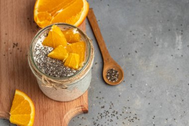 Narenciye ile süslenmiş camda laktozsuz yoğurt ile Chia Seed. Gri arka planda chia tohumlu yoğurt. sağlıklı süper yiyecekler. Sağlıklı yiyecekler. metin için yer.