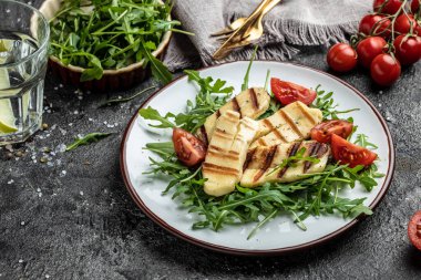 Izgara halloumi peynirli taze salata, domates, kapari, marul ve roka. Ketojenik paleo diyeti. Lezzetli kahvaltı ya da atıştırmalık, temiz yemek, diyet, vejetaryen yemek konsepti. en üstteki görünüm.