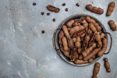 Gri arka planda metal bir tepside lezzetli olgun tamarindler, afiş, menü, metin için tarif yeri, üst görünüm,