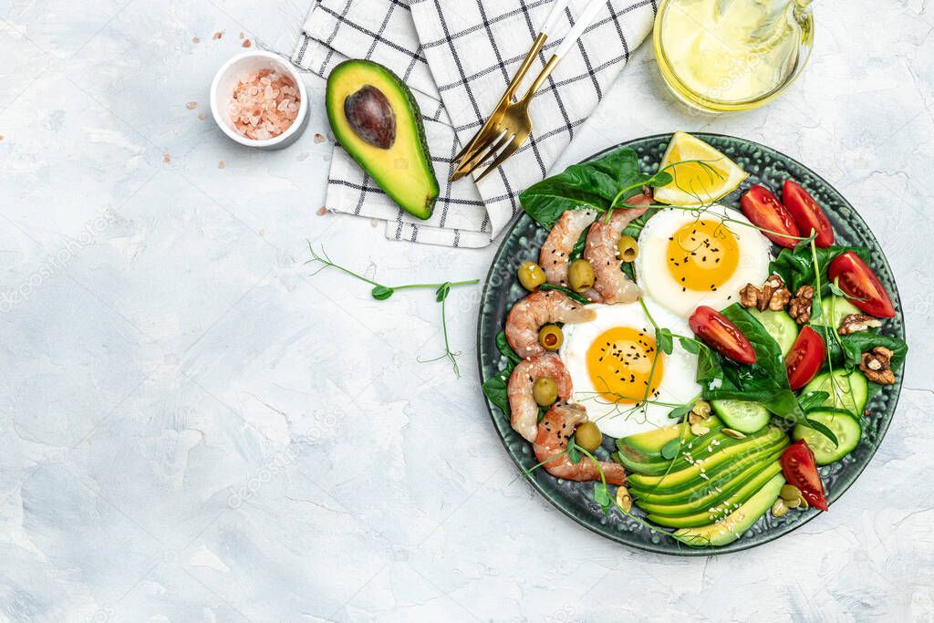 shrimps, prawns, soft fried egg, fresh salad, tomatoes, cucumbers and avocado on a light background. Ketogenic diet breakfast. Keto, paleo lunch. Top view.