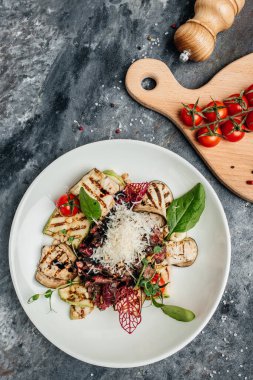 Izgara sebze, fındık, sos ve parmesanla dilimlenmiş biftek barbeküsü. İtalyan mutfağı konsepti. dikey görüntü. Üst Manzara. metin için yer.