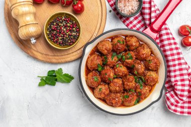 Hafif arka planda tavada domates soslu köfteler, uzun afiş formatında. en üstteki görünüm.