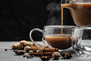 Gri arka planda süt ve baharatlı geleneksel Hint masala çayı. afiş, menü, metin için tarif yeri, üst görünüm.