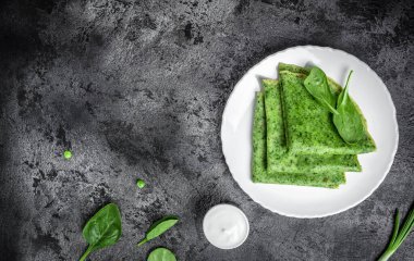 Siyah arka planda ıspanaklı yeşil vejetaryen krepleri. Sağlıklı kahvaltı, vejetaryen yemeği, afiş, yazı için menü tarifi yeri, üst görünüm.