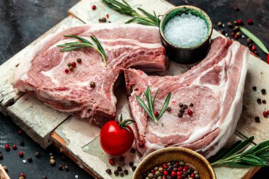 Esmer arka planda baharatlı ve otlu çiğ et. Çiğ domuz eti, pirzola. Restoran menüsü, diyet, yemek kitabı tarifi. Üst görünüm.