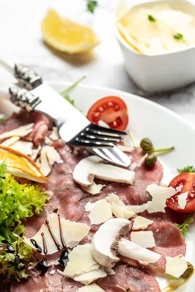 Parmesanlı sığır eti, kapari ve hafif arkaplanlı roka. Soğuk meze. dikey görüntü. Üst Manzara. metin için yer.