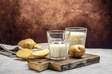Bardakta vejetaryen patates sütü ve çiğ patates. Alternatif bitkisel süt. Süper yiyecek konsepti. Sağlıklı, temiz yemek. Vejetaryen ya da glütensiz diyet. en üstteki görünüm.