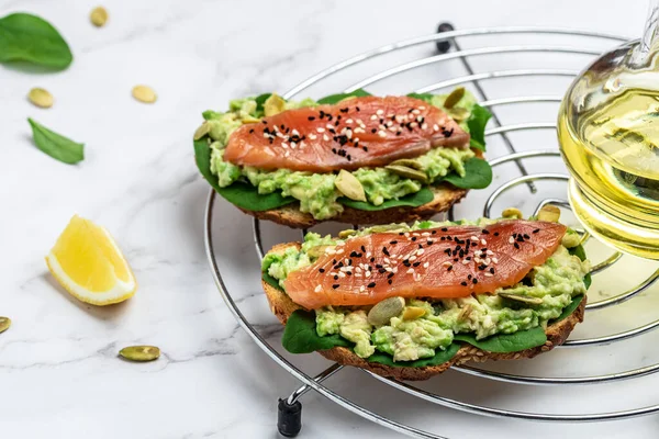 Two toasts whole grain bread with avocado paste and salmon. keto paleo diet. Restaurant menu, dieting, cookbook recipe top view.