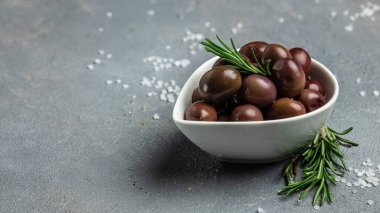 Gri arka planda küçük bir kasede taze biberiyeli pembe zeytinler. Uzun afiş biçimi. en üstteki görünüm.