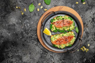 Lezzetli kahvaltı ya da somon balığı, avokado, ıspanak, fındık, ayçekirdeği, kırmızı balık ve guacamole ile tost. Sağlıklı, temiz yemek. Vejetaryen ya da glütensiz diyet. Üst görünüm, boşluk kopyala.