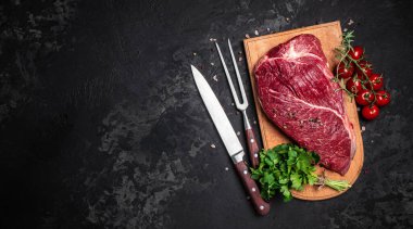 Çiğ et, siyah arka planda biftek, pişmeye hazır bir parça biftek. Uzun afiş biçimi. en üstteki görünüm.