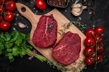 İki taze çiğ biftek ve arkaplanda pişmeye hazır baharatlar. Mutfak, yemek pişirme, konsept. afiş, menü, metin için tarif yeri, üst görünüm.