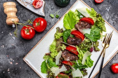 Tavuk ciğeri ve salata yaprakları, parmesan peyniri ve vişneli domates. Lezzetli dengeli gıda konsepti.