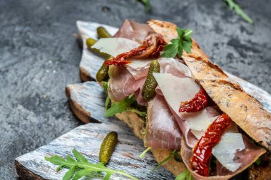 Prosciutto sandviçi, jambonlu Ciabatta, kurutulmuş domatesler, turşu, parmesan ve roka, afiş, menü, metin için tarif yeri.,