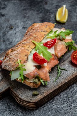 Ev yapımı ciabatta ekmekli sandviçler, tuzlu somon balığı, parmesan peyniri, kapari, vişneli domates ve roka, restoran menüsü, diyet, yemek kitabı tarifi üst görünümü,